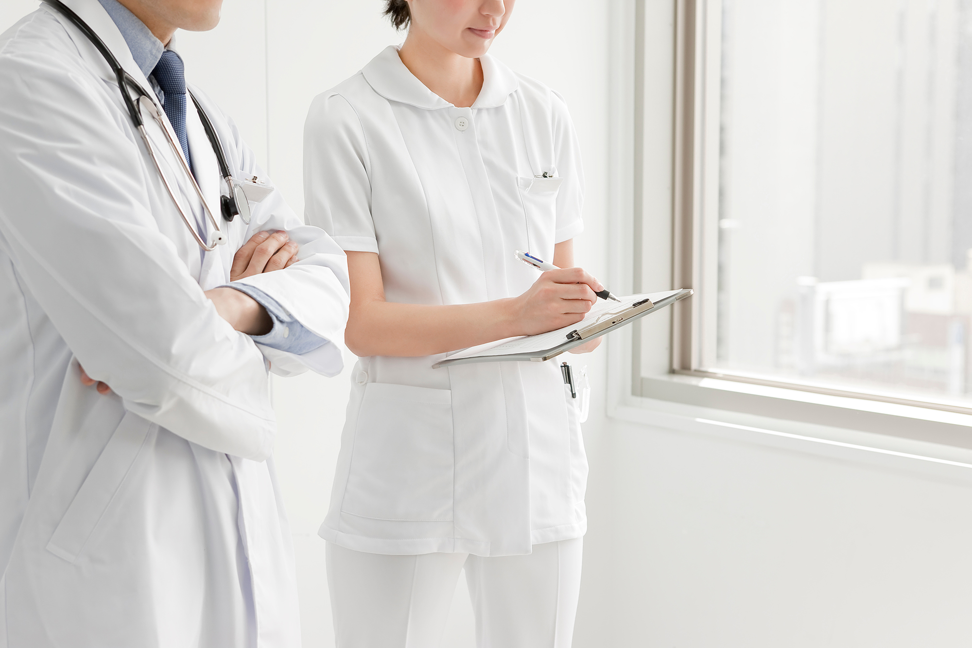 カルテを手に打ち合わせをする医師と看護師 - 主治医・医療機関との緊密な連携体制を表すイメージ